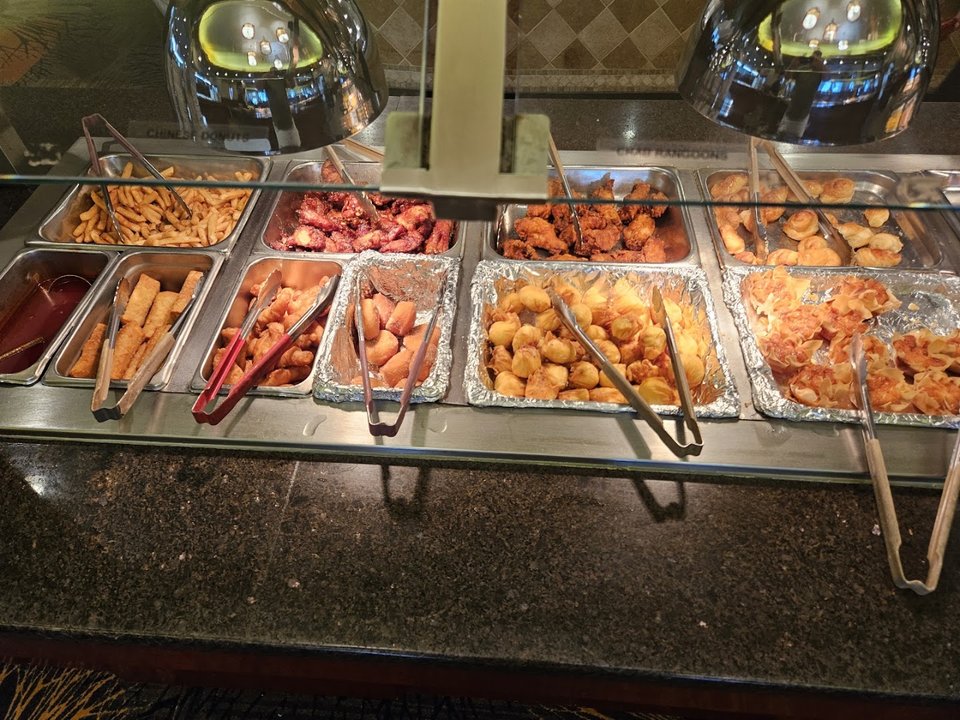 Buffet trays with assorted Asian dishes.
